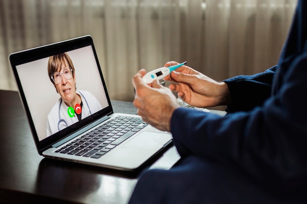 Больной человек с лихорадкой делает онлайн-медицинскую консультацию со своим врачом из дома