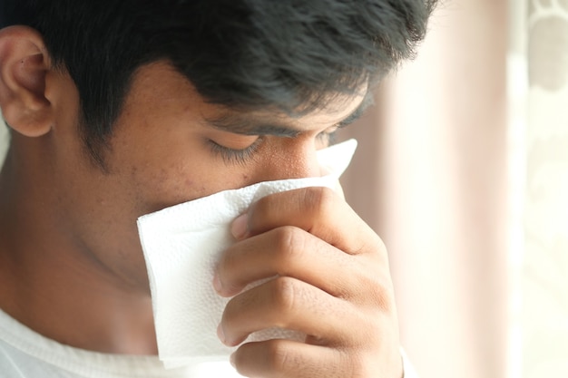 Sick man with flu blow nose with napkin.