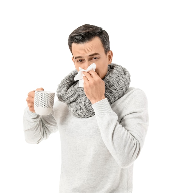 Sick man with hot tea on white surface