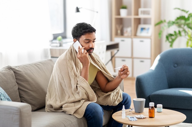 sick man with thermometer calling on smartphone