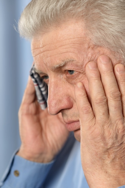 Sick old man standing on brown background