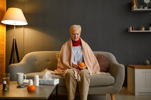 Sick old woman decide what to choose orange or pills. Medical treatment versus organic fruit eating