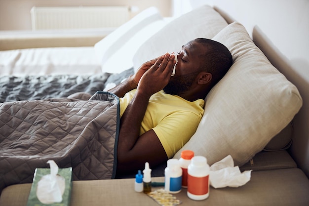 Persona malata che si soffia il naso sdraiato a letto