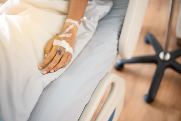 the sick persons hand is wearing a blue dress lying on the bed in the hospital