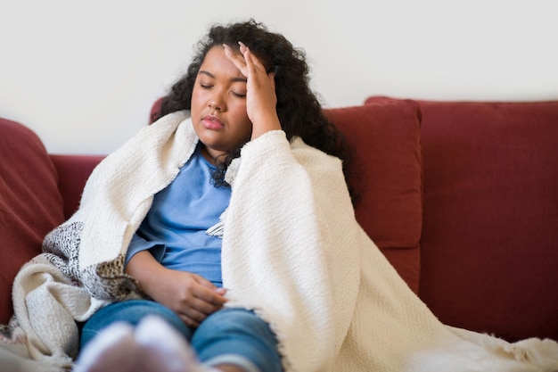 Photo sick plus size curly woman sitting on couch at home