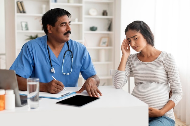 Photo sick pregnant indian woman feeling unwell during meeting with doctor in clinic