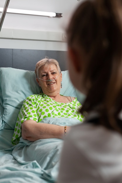 Photo sick retired grandmother talking with grandchild while resting in bed