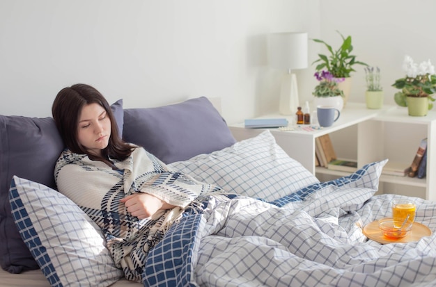 白い部屋のベッドでお茶と病気の十代の少女