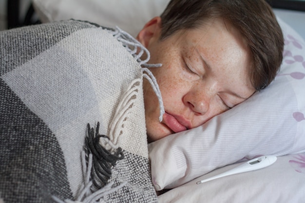 Sick teenage boy sleeping on his bed