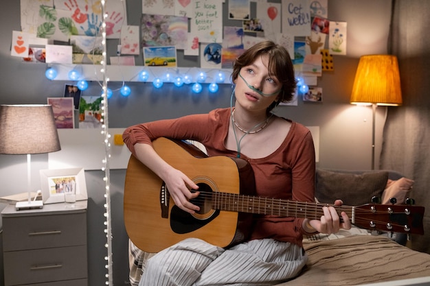 Sick teenage girl learning to play guitar