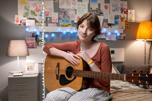 Sick teenage girl with guitar sitting at hospital ward