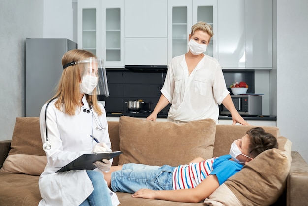 Sick teenager boy lying on sofa while doctor doing checkup