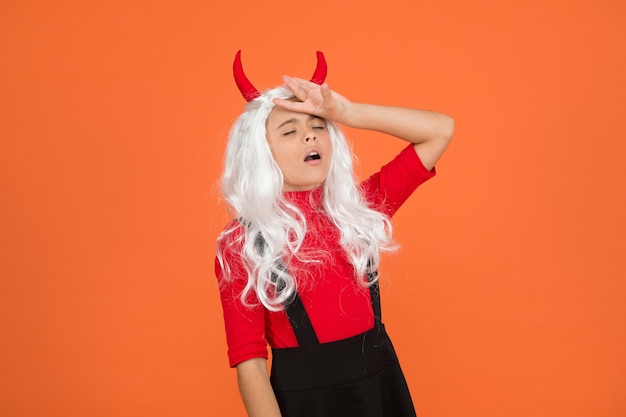 Sick and tired. tired kid has long white hair wig. childhood\
happiness. teen girl ready to celebrate costume party. funny red\
imp horns. devil costume. happy halloween. child in devil\
horns.