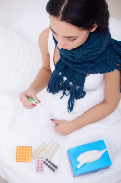 Sick woman in bed with thermometer is having high temperature fever 