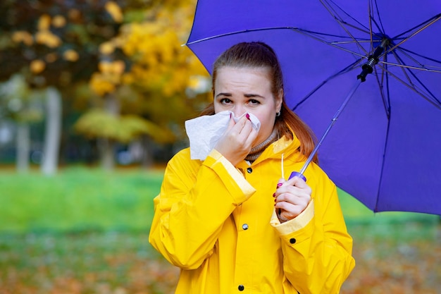 Sick woman blows her nose and sneezes outdoors during an epidemic of flu and colds the female suffer...