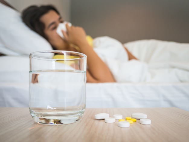 Sick woman covered with a blanket lying in bed with high fever and a flu.