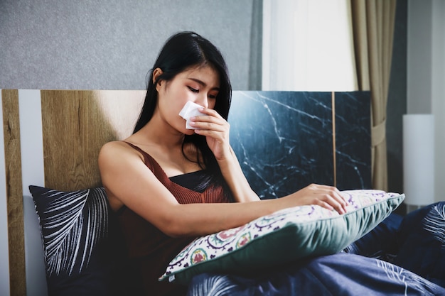 Sick woman covered with a blanket lying in bed