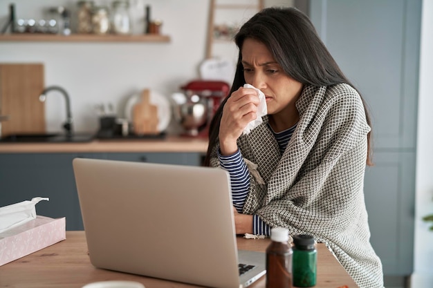 Sick woman in front of laptop at home