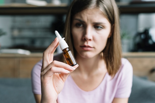 Photo sick woman holding nasal spray in her hand