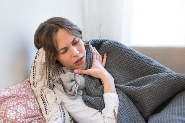 Sick woman lying on sofa and trembles