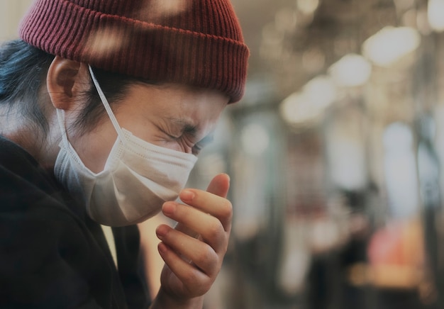 sick woman in a mask sneezing in a train during coronavirus pandemic