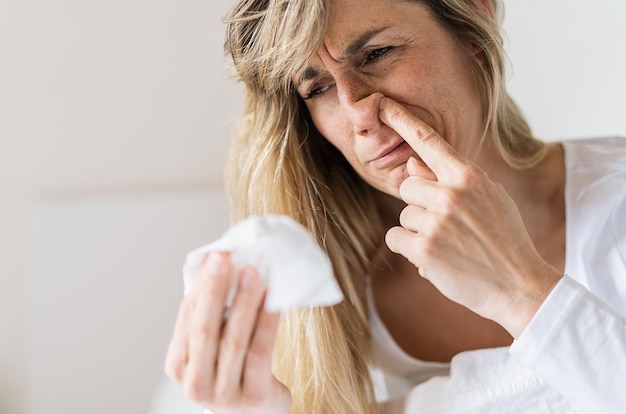 Sick woman Picking his nose Upset ill european lady sits in bed blowing and picks her nose using paper napkin tissue Cold And Flu Concept