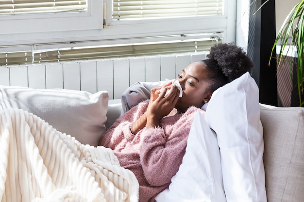 Sick woman on a sofa blowing her nose