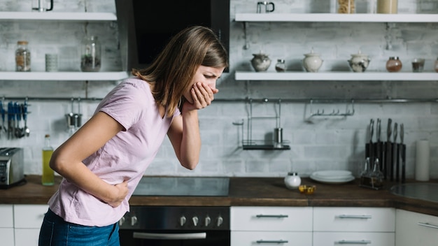 Foto donna ammalata che soffre dalla nausea che sta nella cucina