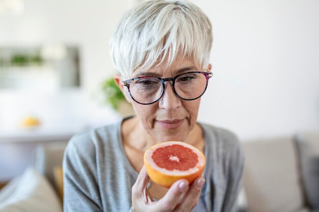 Sick woman trying to sense smell of half fresh orange, has\
symptoms of covid-19, corona virus infection - loss of smell and\
taste. one of the main signs of the disease.