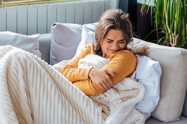 Sick woman with cramps lying on a sofa