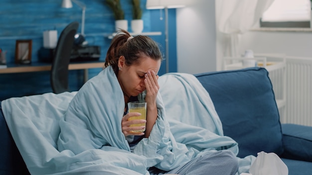 Sick woman with headache drinking effervescent vitamin drink