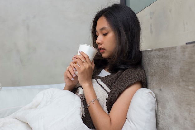 Sick young asian beautiful woman drinking water in bed