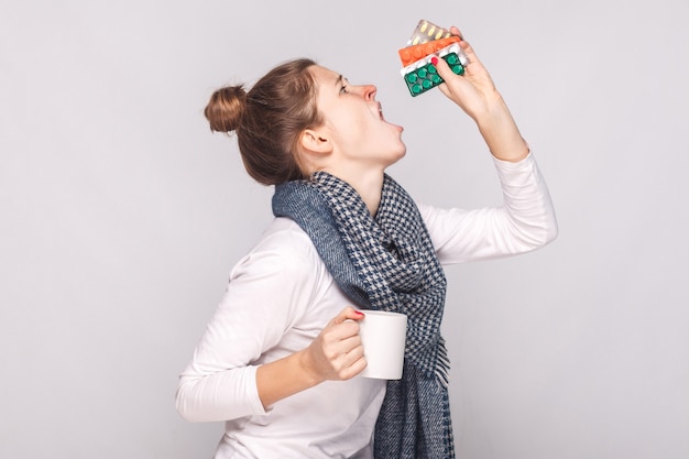 Sick young woman holding cup with tea many pills antibiotics