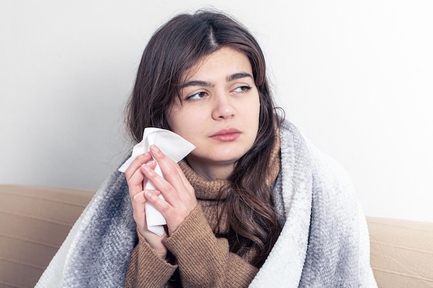 A sick young woman at home on the sofa with a cold