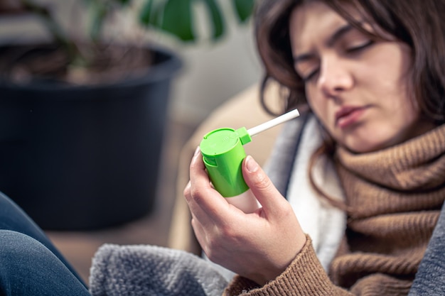 A sick young woman using cough spray