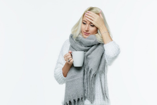 Photo sickness cute young blonde woman wrapped scarf having headache, touching her temple and closed eyes, closeup. cold, virus, migraine, flu season concept.