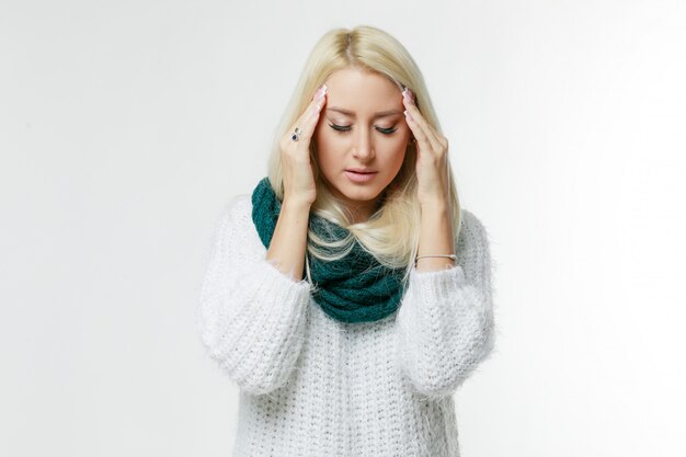 Photo sickness cute young blonde woman wrapped scarf having headache, touching her temple and closed eyes, closeup. cold, virus, migraine, flu season concept.