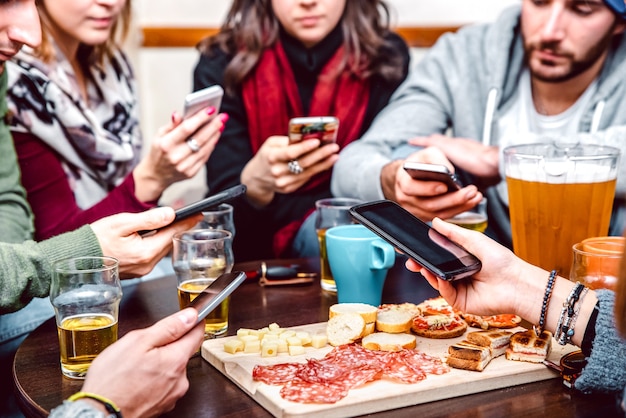 Side angle view of hands with cellphones at beer bar restaurant