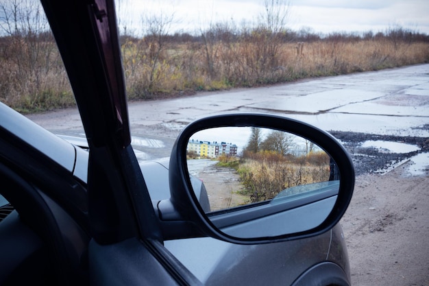 Боковое зеркало серого автомобиля с отражающей улицей