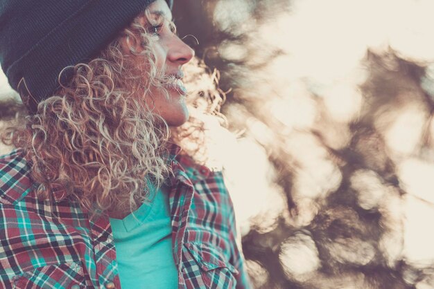 Side portrait of cheerful happy woman in outdoor leisure activity alone with bokeh light nature background Active female people enjoying outdoors and travel vacation Beautiful curly hair Copy space