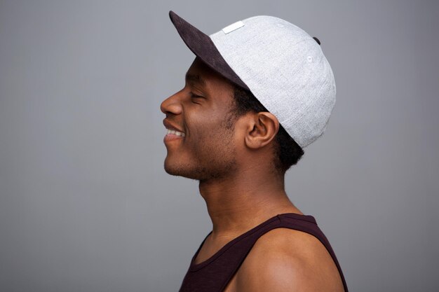 Photo side portrait of cool african american guy with cap against gray wall