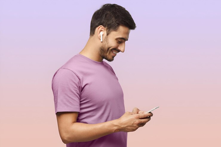 Photo side portrait of handsome man in purple tshirt looking at screen of smartphone surfing internet