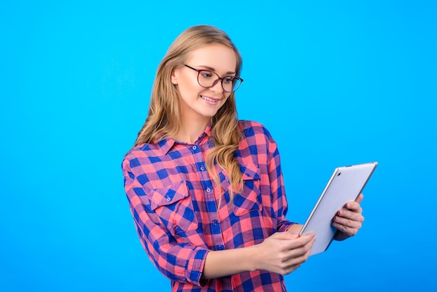 Side profile half-turned portrait of cheerful lovely sweet cute charming beautiful kind with long blonde hair manager agent checking information news on pad isolated on blue background