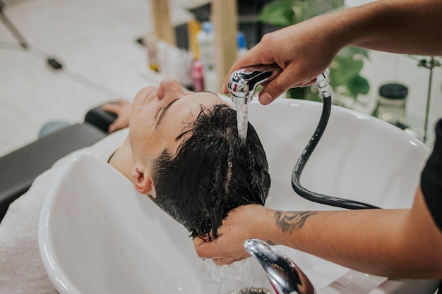 Foto mani del barbiere del tiro laterale che lavano i capelli del suo cliente