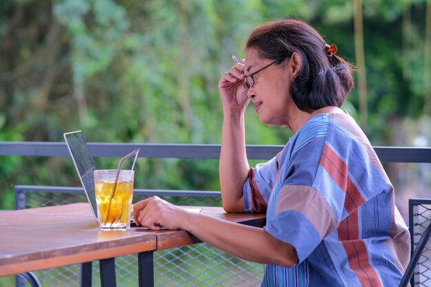 Фото Вид сбоку женщина средних лет работает на своем ноутбуке на открытом пространстве
