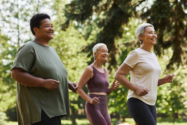 Side view active senior women running outdoors in park and enjoying sports