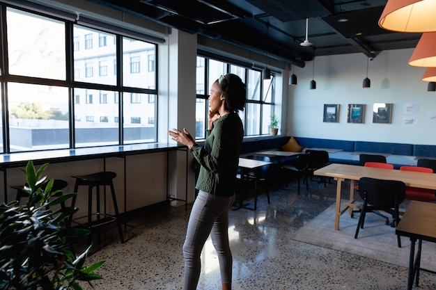 아프리카계 미국인 젊은 사업가 여성이 크리에이티브 사무실에서 휴대 전화로 이야기하는 측면 전망