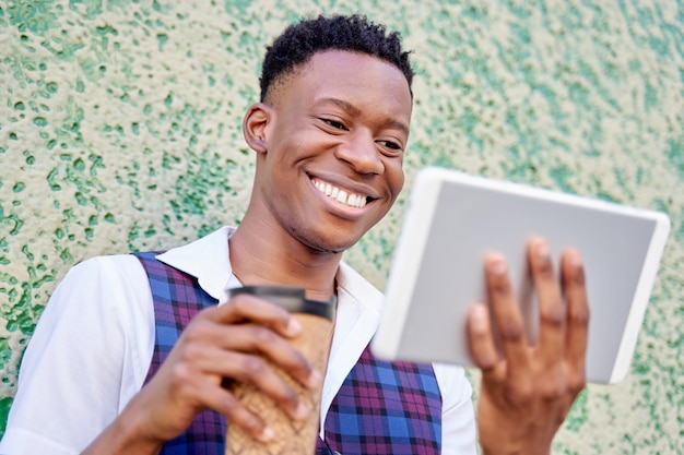 Side view african american young man with tablet computer and
take away coffee