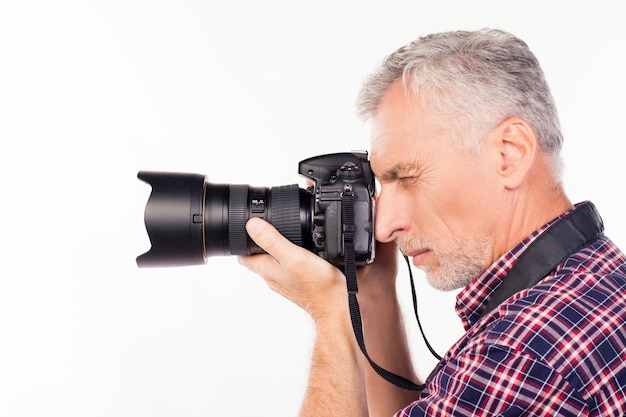 Side view of aged photographer taking a photo