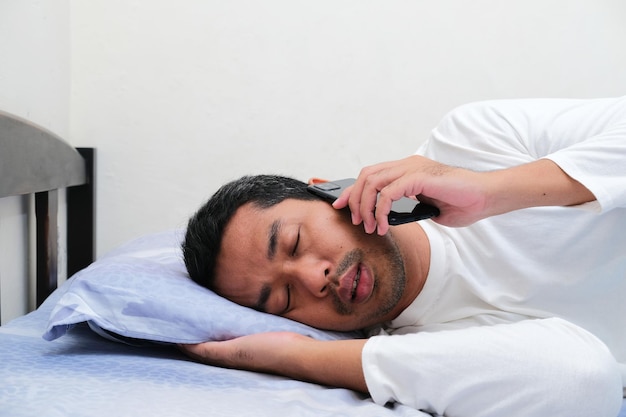 Side view of Asian man answering a phone call until he sleeping